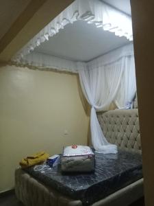 ein Bett in einem Zimmer mit Himmelbett und einem Koffer in der Unterkunft Rosslyn suites in Juja + 2 Fotos