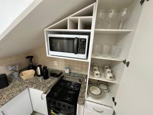 Duplex Por do Sol a Beira Mar في فلوريانوبوليس: مطبخ صغير مع ميكروويف وموقد