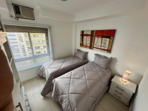 Duplex Por do Sol a Beira Mar في فلوريانوبوليس: غرفة نوم بها سريرين ونافذة