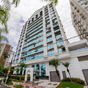 Duplex Por do Sol a Beira Mar في فلوريانوبوليس: مبنى شاهق أمامه أشجار النخيل