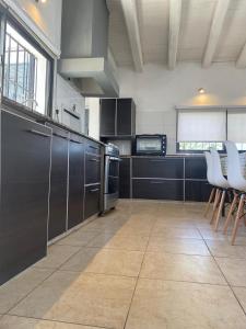 a large kitchen with stainless steel appliances and white chairs at summer house in La Porteña +6 photos
