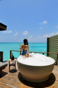 FushifaruFushifaru Maldives with 50 percent off on sea plane roundtrip 04 nights & above的一位女子坐在甲板上的浴缸里，眺望着大海。 更多60张照片