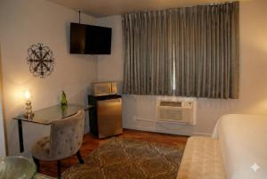 un piccolo soggiorno con un tavolo e una scrivania con un forno a microonde di The Crest Motel a Sterling