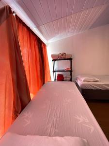 a small bedroom with two beds and an orange curtain at Quarto Duplo Casal Jd Botânico in Curitiba