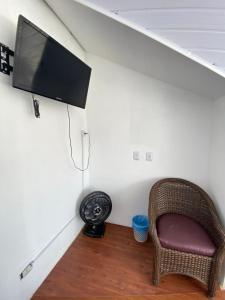 a room with a chair and a flat screen tv on a wall at Quarto Duplo Casal Jd Botânico in Curitiba