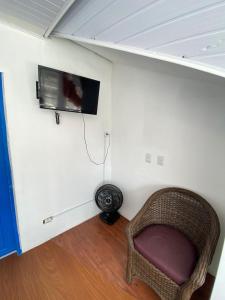 a room with a chair and a tv on a wall at Quarto Duplo Casal Jd Botânico in Curitiba