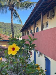 a yellow flower in front of a building with a palm tree at Villa Di Verona Charm Hotel in Guarujá