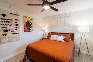 een slaapkamer met een oranje bed en een plafondventilator bij Full complex 8 Separate 2 bedroom 1 bath units in Cocoa Beach