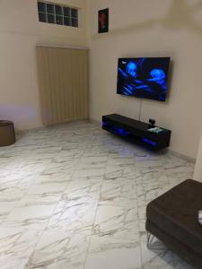 sala de estar con suelo de baldosa y TV de pantalla plana en Forson's cozy spacious home, en Takoradi