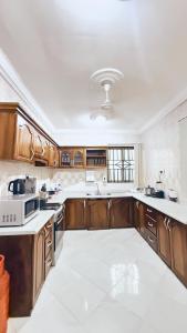 Una cocina grande con gabinetes de madera y piso blanco. en Forson's cozy spacious home, en Takoradi
