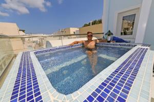 a man in a swimming pool on top of a house at Asterolithos in Fira