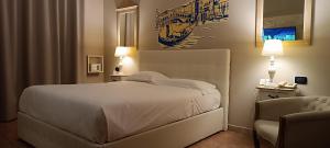 Hotel Palladium في Monastir: غرفة نوم بسرير ابيض وكرسي