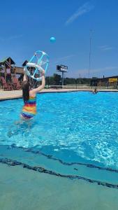 una donna in una piscina che tiene un ombrello di Bryan North College Station KOA Holiday a Bryan