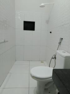 a white bathroom with a toilet and a shower at hospedaria Cantinho da Rosa in Santo Amaro