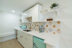 a kitchen with white cabinets and a sink at THE JUNI Studio Surf Paradise in Heart of Cocoa Beach in Cocoa Beach