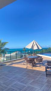 a patio with a table and chairs and an umbrella at Condomínio encantador com piscina in Ipojuca +10 photos