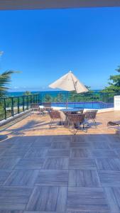 a patio with a table and an umbrella at Condomínio encantador com piscina in Ipojuca