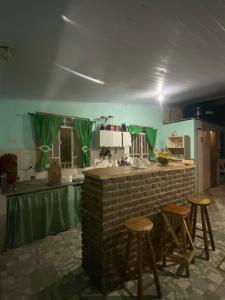 a kitchen with a brick counter and stools in it at Pousada Matriz in São Thomé das Letras