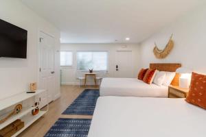 Un dormitorio con dos camas y un televisor de pantalla plana. en THE JUNI Stunning Studio Walk to Everything, en Cocoa Beach