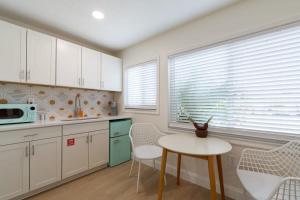 Una cocina con gabinetes blancos y una mesa y sillas. en THE JUNI Stunning Studio Walk to Everything, en Cocoa Beach 24 fotos más