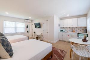 a bedroom with two beds and a table and a kitchen at THE JUNI - Studio Steps to Beach Downtown Cocoa in Cocoa Beach