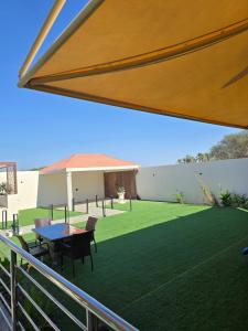 patio con tavolo e sedie su un prato di Algharam resort a Ḩaḑīb