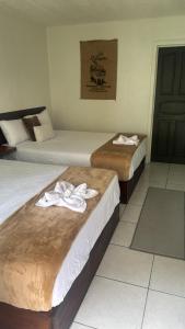 two beds in a hotel room with towels on them at Basecamp Monteverde in Monteverde Costa Rica
