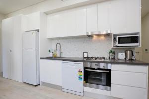 a kitchen with white cabinets and a stove top oven at Hoffy's Place - Modern one bedroom with AC in Sydney