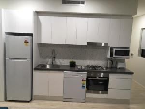 a kitchen with white cabinets and stainless steel appliances at Hoffy's Place - Modern one bedroom with AC in Sydney +3 photos
