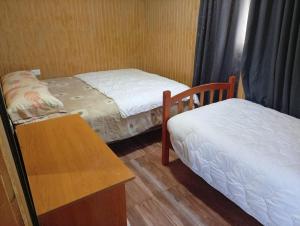 a small room with two beds and a table at Cabaña 4 Acogedora en un entorno natural in Curacautín