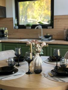 einen Tisch mit Weingläsern und eine Vase mit Blumen in der Unterkunft Kolibe Doftana in Trăisteni