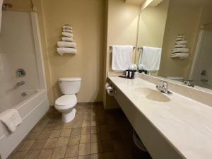 um banheiro com vaso sanitário, pia e banheira em Northern Greens Resort and Conference Centre em Nipawin