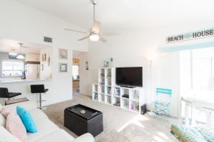 a living room with a white couch and a tv at Beachside Oasis at Villages of Seaport in Cape Canaveral