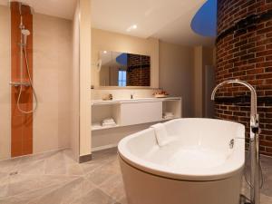 a bathroom with a bath tub and a mirror at Gutshotel Odelzhausen in Odelzhausen