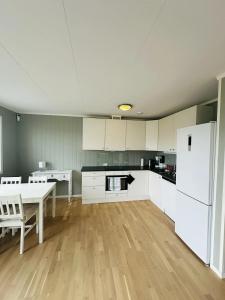 a kitchen with a table and a white refrigerator at Nydelig perle ved Tyrifjorden  +2 photos