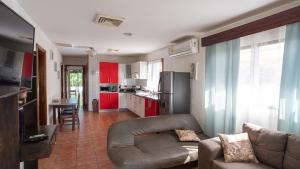 坦波Pura Vida Villa! Beachfront Golf and Country Club Los Delfines 24 hours security的带沙发的客厅和带红色橱柜的厨房