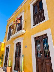 Santuario 71 Lofts and apartments في غواناخواتو: مبنى أصفر به نوافذ وشرفة وأبواب