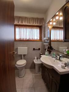 a bathroom with a toilet and a sink and a mirror at Casa di Viaggiatori Ciampino in Ciampino +11 photos