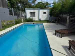 ein blauer Pool mit einer Bank und einem Haus in der Unterkunft Excelente Casita en Paso in Paso de la Patria