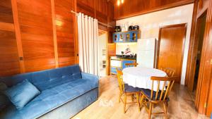 uma sala de estar com um sofá azul e uma mesa em ASA | Chalés Vô Luiz | 2QT | Ar Cond. | Churrasqueira | Próx. à Praia em Gravata