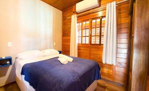 um quarto com uma cama com lençóis azuis e uma janela em ASA | Chalés Vô Luiz | 2QT | Ar Cond. | Churrasqueira | Próx. à Praia em Gravata