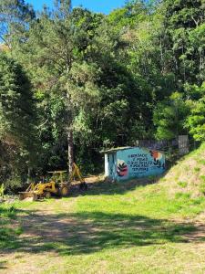 Ein Schuppen und ein Traktor auf einem Feld mit Bäumen in der Unterkunft Studio com hidromassagem em Guararema in Guararema