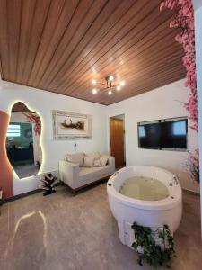 ein großes Bad mit einer Badewanne und einem TV in der Unterkunft Studio com hidromassagem em Guararema in Guararema