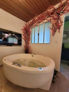 eine große Badewanne in einem Raum mit Fenstern in der Unterkunft Studio com hidromassagem em Guararema in Guararema + 14 Fotos