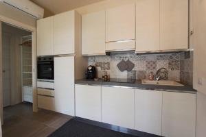 Una cocina con gabinetes blancos y un fregadero. en Il Giardino di Angelo, en Cava dʼAliga