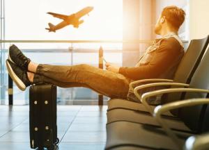 a man sitting in an airport with his feet on a suitcase at Le Shot tours Hotel in Al Jafr