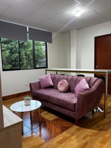 a living room with a purple couch and a table at Amazon Garden Suites - Recojo del aeropuerto incluido in Pucallpa