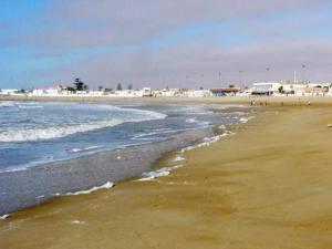 a beach with the ocean and a group of people at Maison Ait alla tantan in Tan-Tan Plage