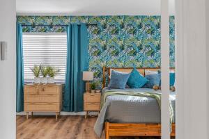 a bedroom with a bed with blue walls and blue curtains at Downtown Cocoa Beach Townhome- Walk to Everything in Cocoa Beach