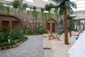 a courtyard with a stone wall and a palm tree at Aquapark Reda Resort - jedyne noclegi w Aquaparku Reda in Reda